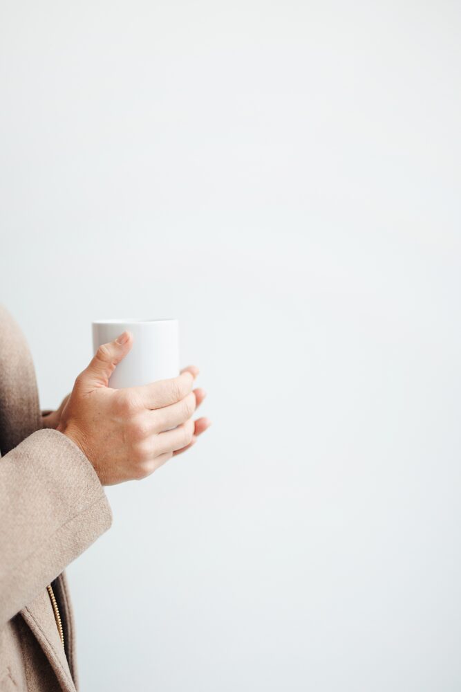 Hands holding a white mug against a white background