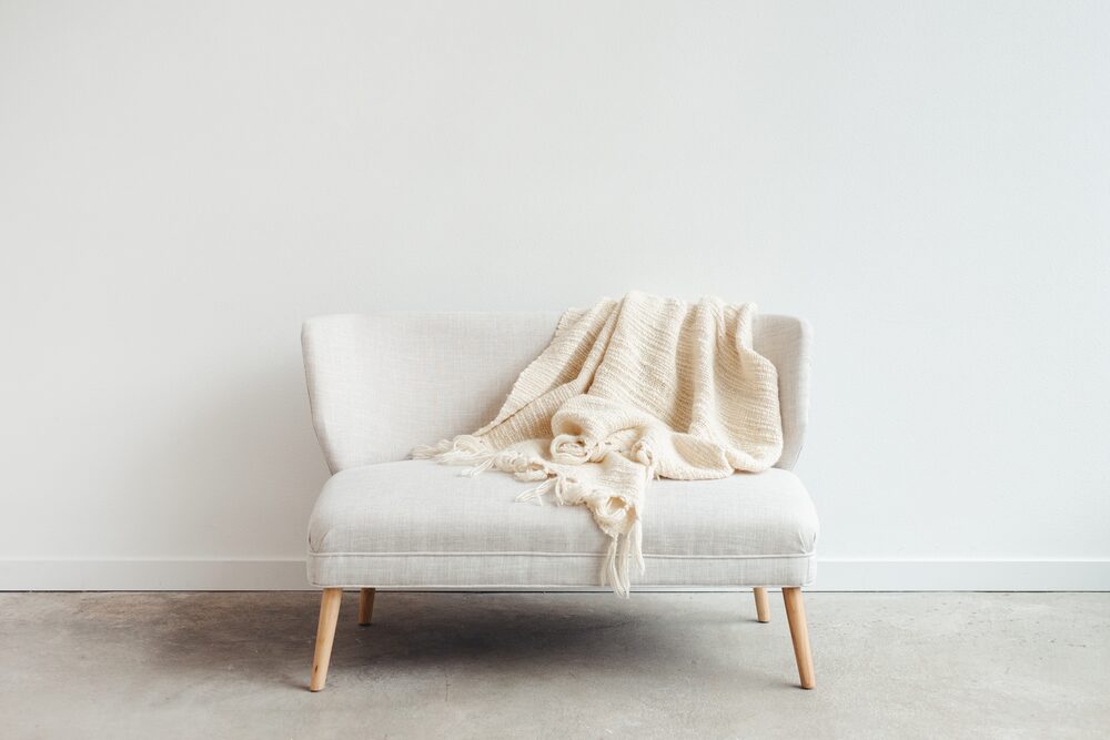Cream armchair with a draped throw blanket in a white room