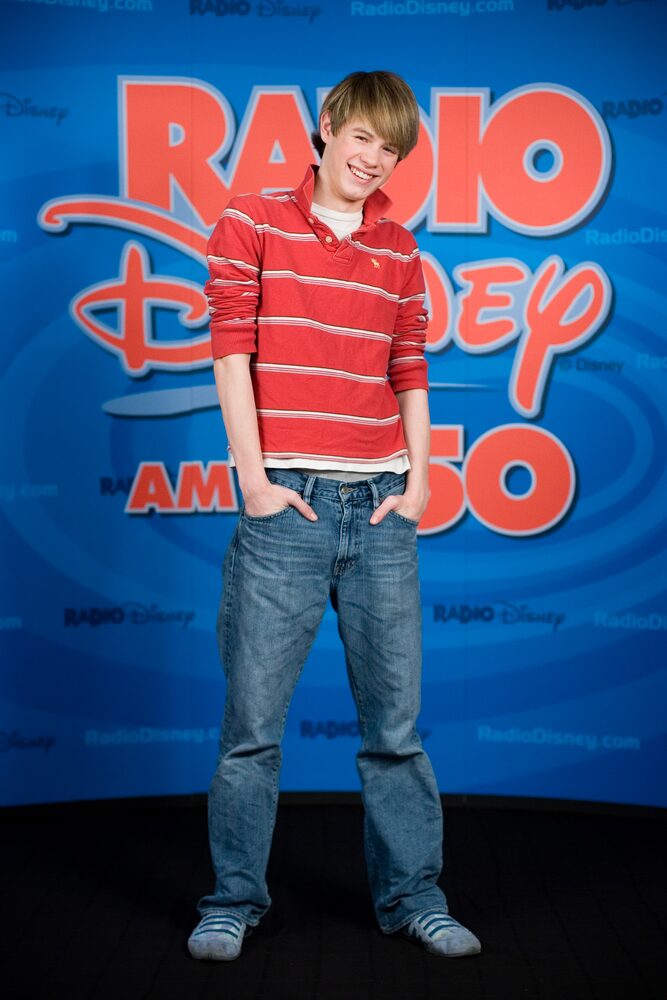 Teen boy in a red striped shirt in front of a radio station backdrop