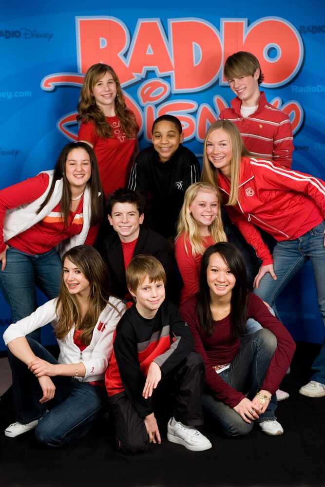 Group of teens in red and white posed in front of a radio station backdrop
