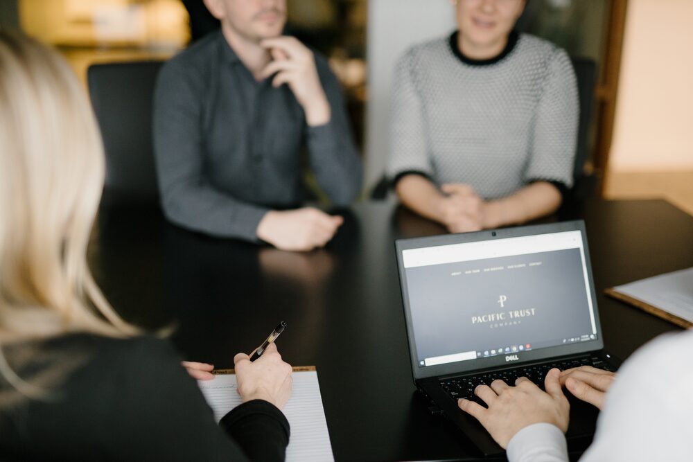 Colleagues in discussion around a conference table with a laptop