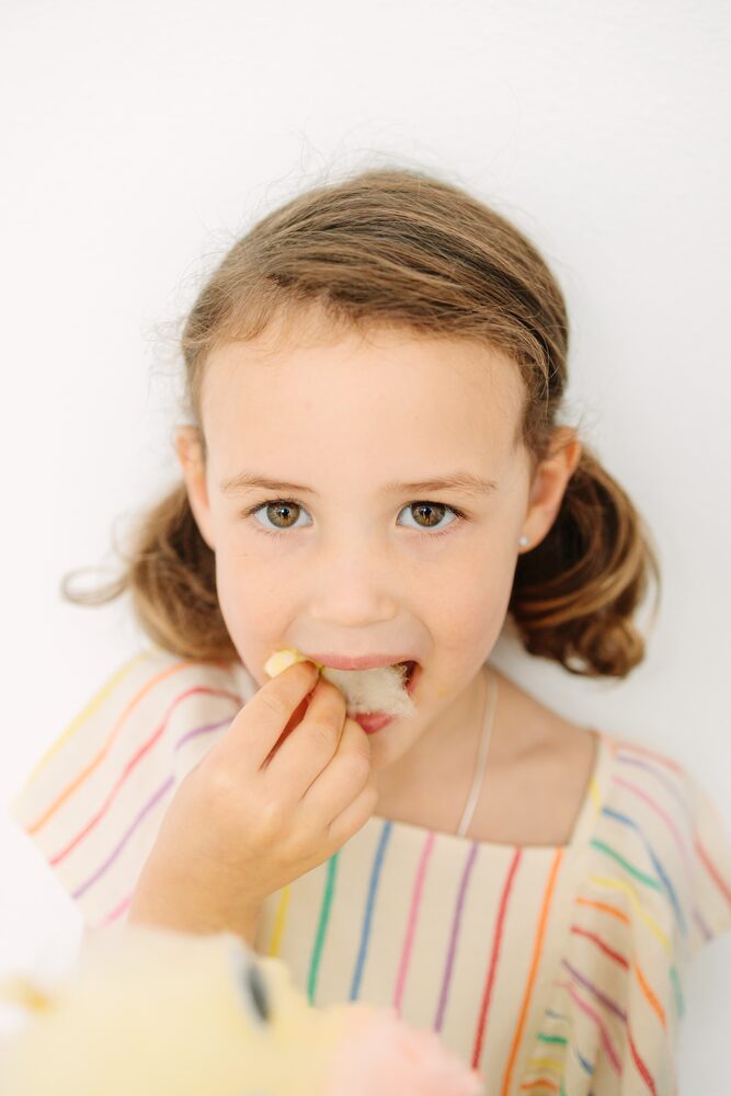 Close-up of a girl in a striped dress tasting a treat