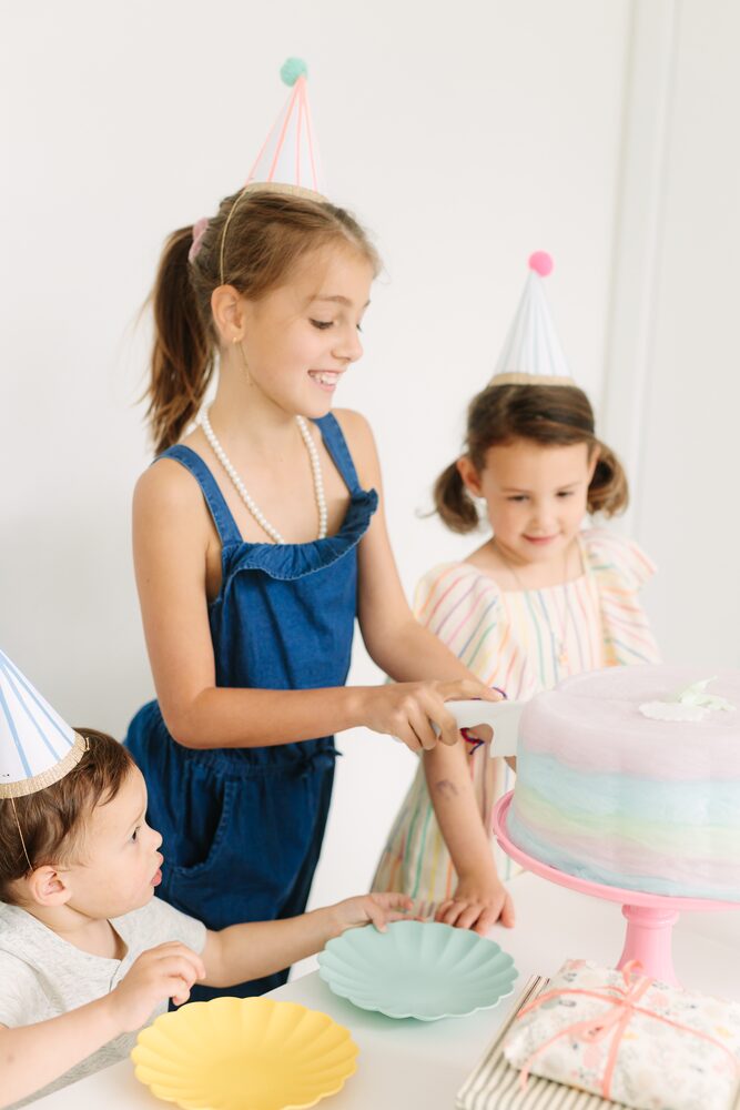 Children in party hats gathered around a cake
