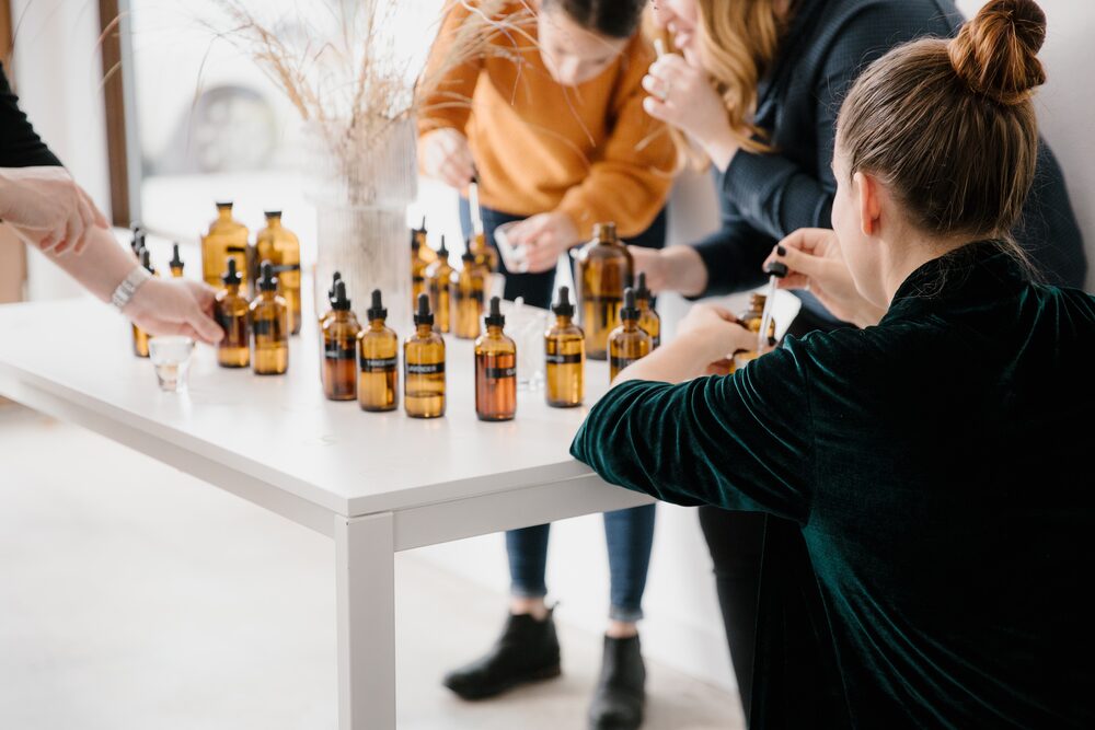 Guests sampling small bottles at a white table during a workshop