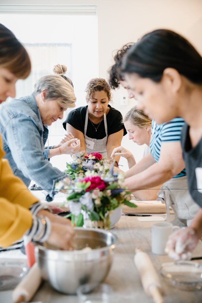 Cooking class participants gathered around a bowl at a kitchen island