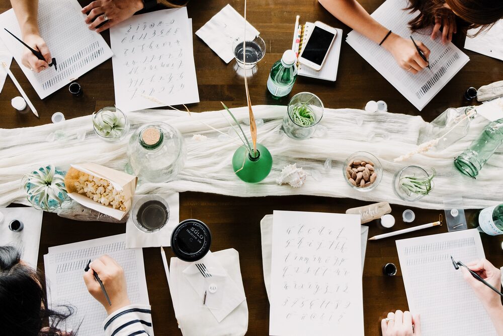 Overhead view of calligraphy practice sheets and pens on a table