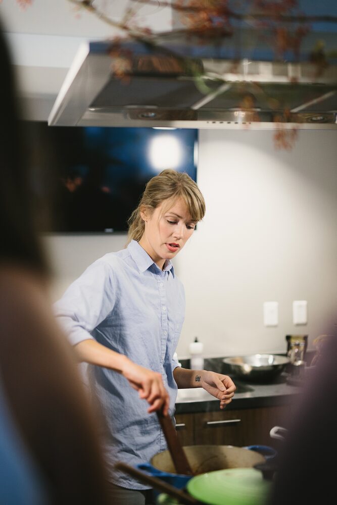 Woman in a blue shirt cooking at a kitchen stove