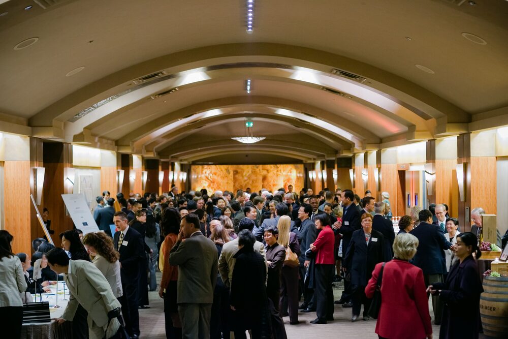 Wide view of a crowded reception in a hall with a barrel-vaulted wooden ceiling