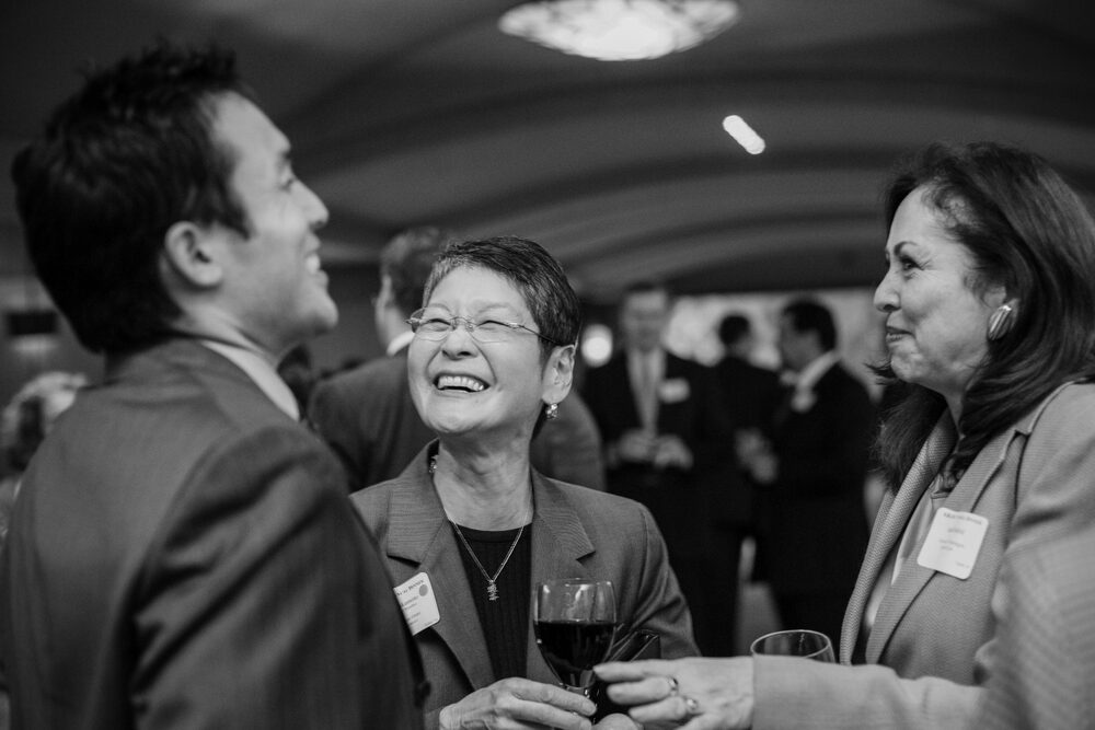 Black and white photo of guests laughing at a reception