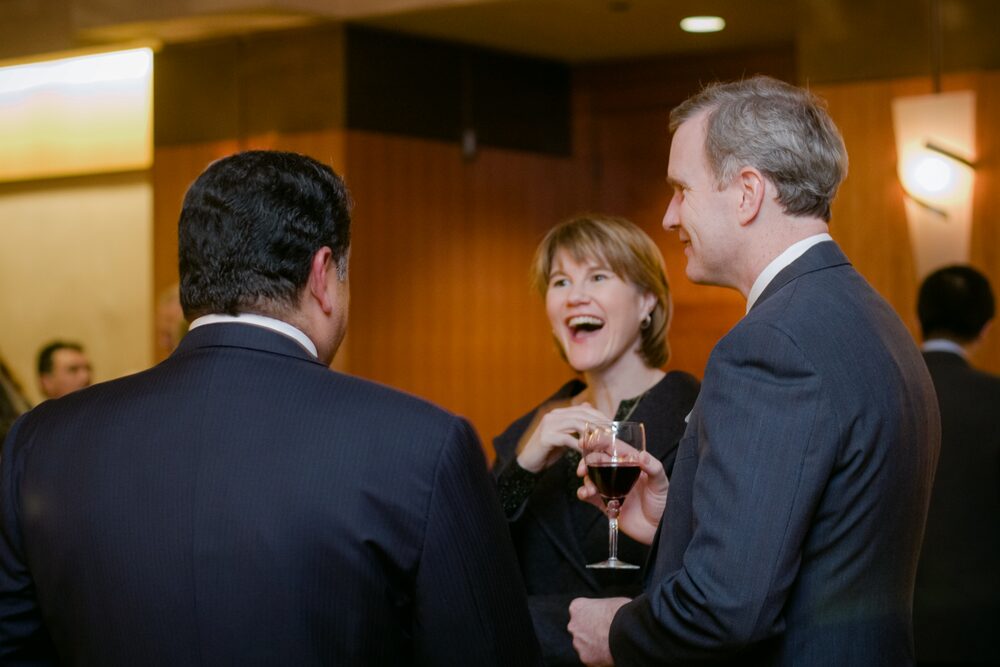 Guests laughing together over drinks at a reception