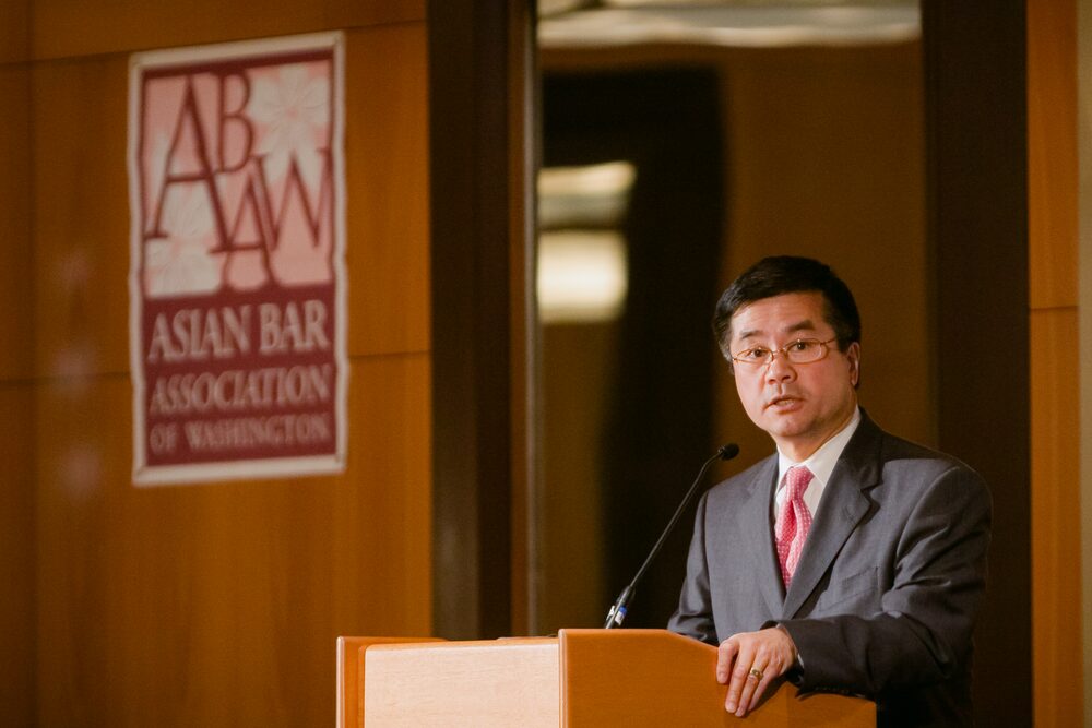 Speaker at a podium beneath an event sign
