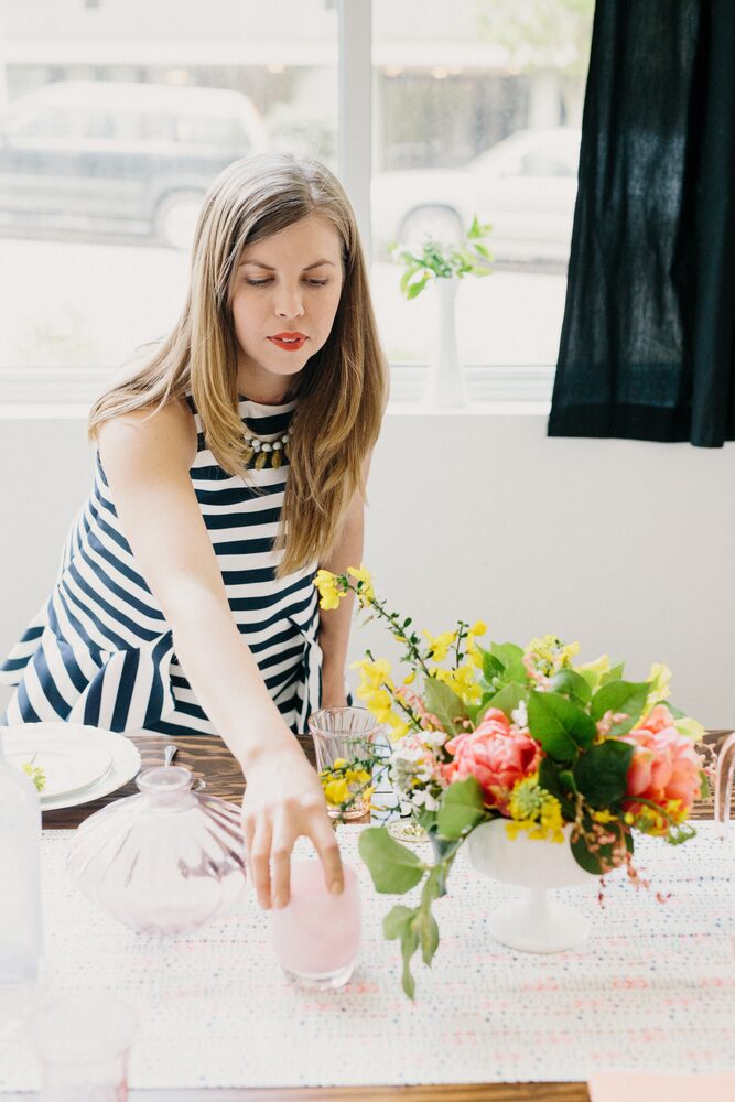 Woman in a striped top arranging flowers by a window
