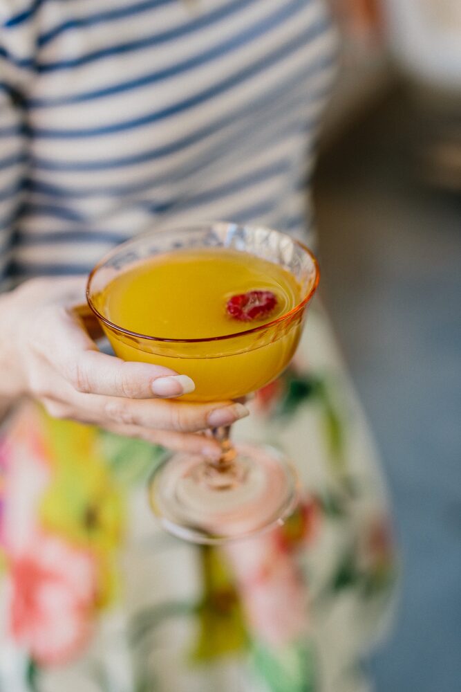Hand holding a cocktail garnished with a flower