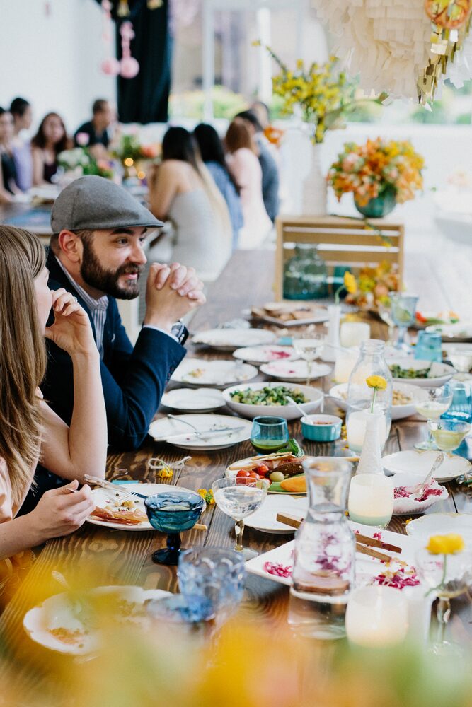 Man in a cap laughing at a long brunch table