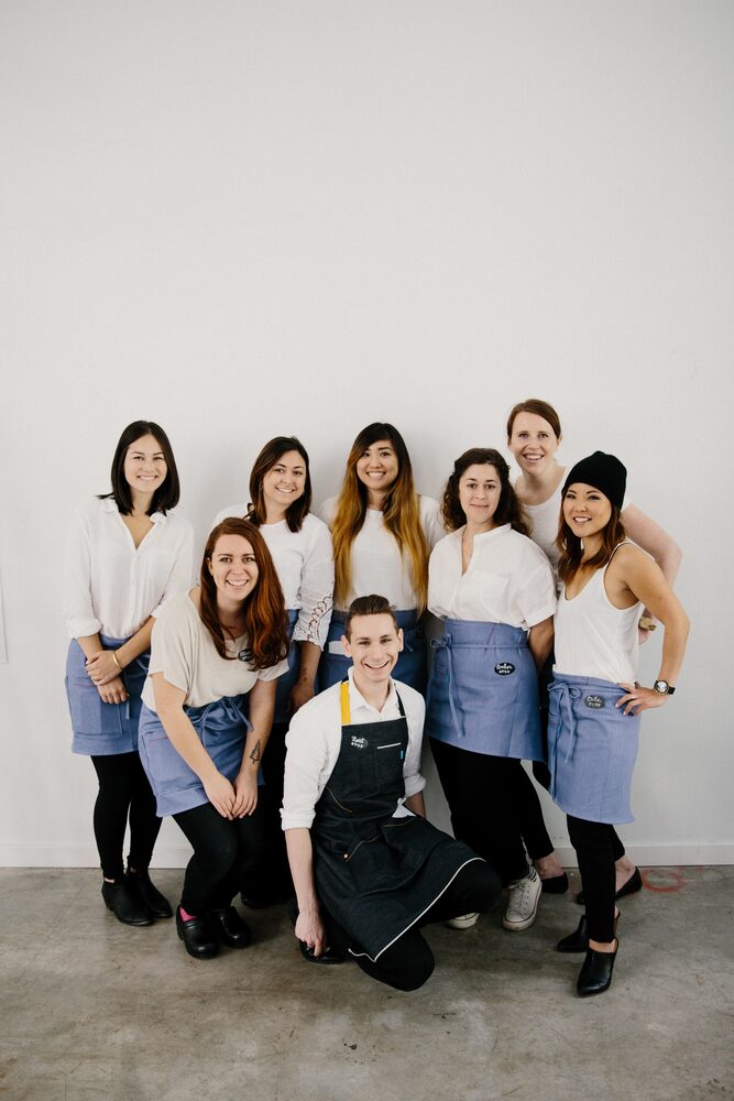 Group of women in white tops and aprons posed together in a studio