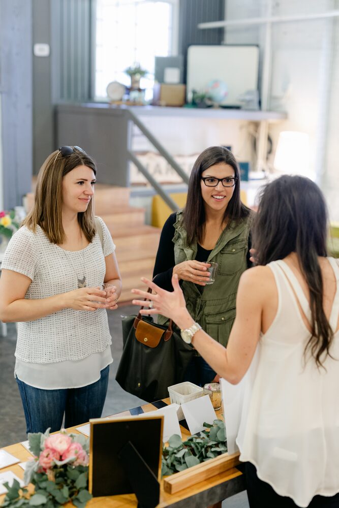 Three women talking at a vendor table