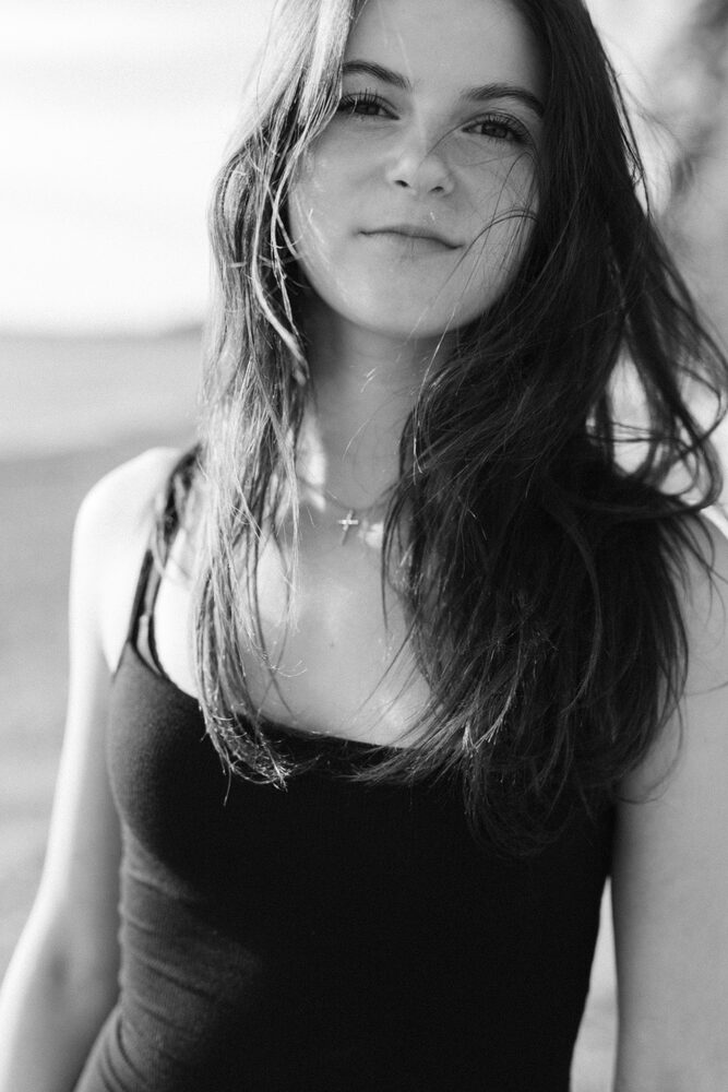 Black and white portrait of a woman with wind-blown hair in a dark tank top