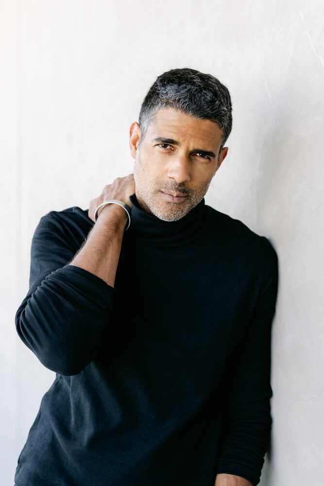 Man in a black turtleneck with his hand at the back of his neck