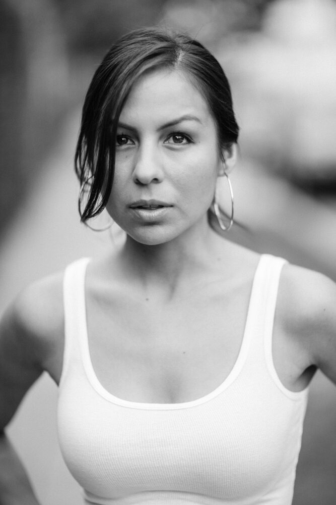 Black and white portrait of a woman in a white tank top with hoop earrings