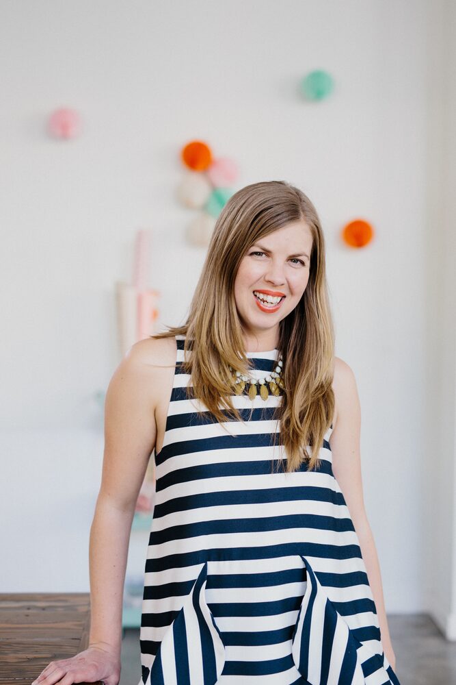 Woman in a striped dress standing in front of pastel paper decorations