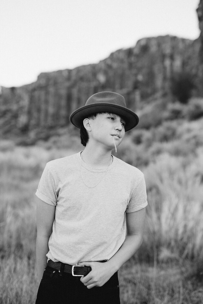 Black and white portrait of a person in a hat and t-shirt in a rocky landscape