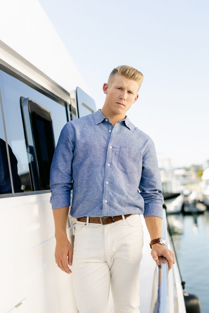 Man in a blue button-down shirt standing on a dock beside a boat