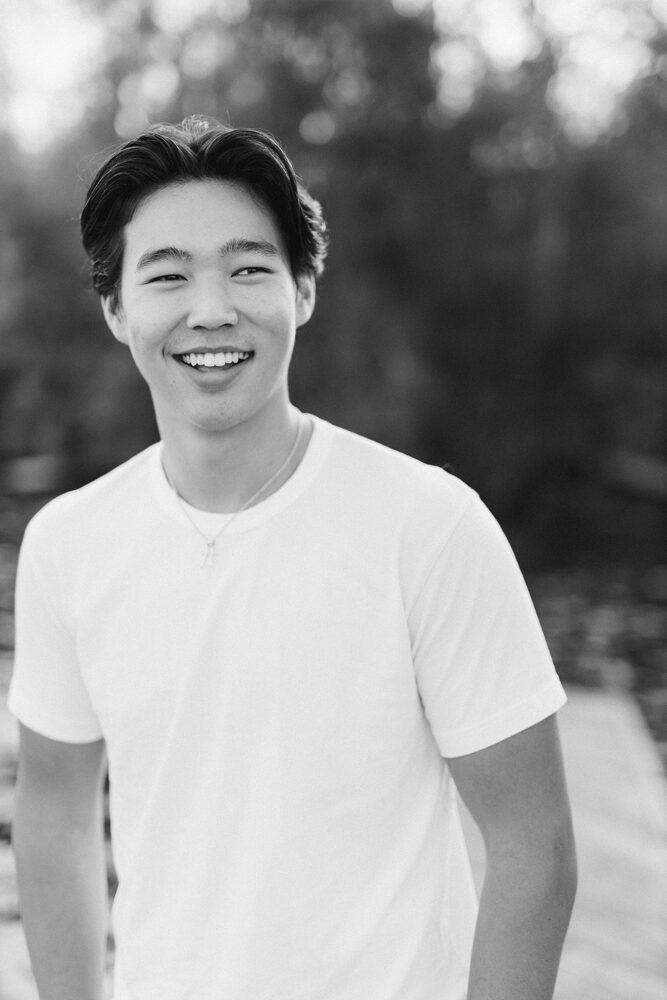 Black and white portrait of a young man in a white t-shirt, laughing outdoors