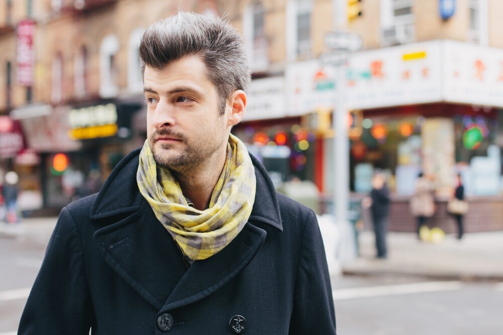 Man in a peacoat and patterned scarf on a busy city street