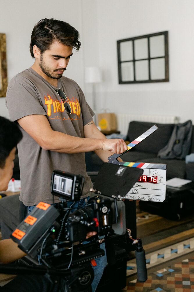 Crew member holding a clapperboard beside a cinema camera