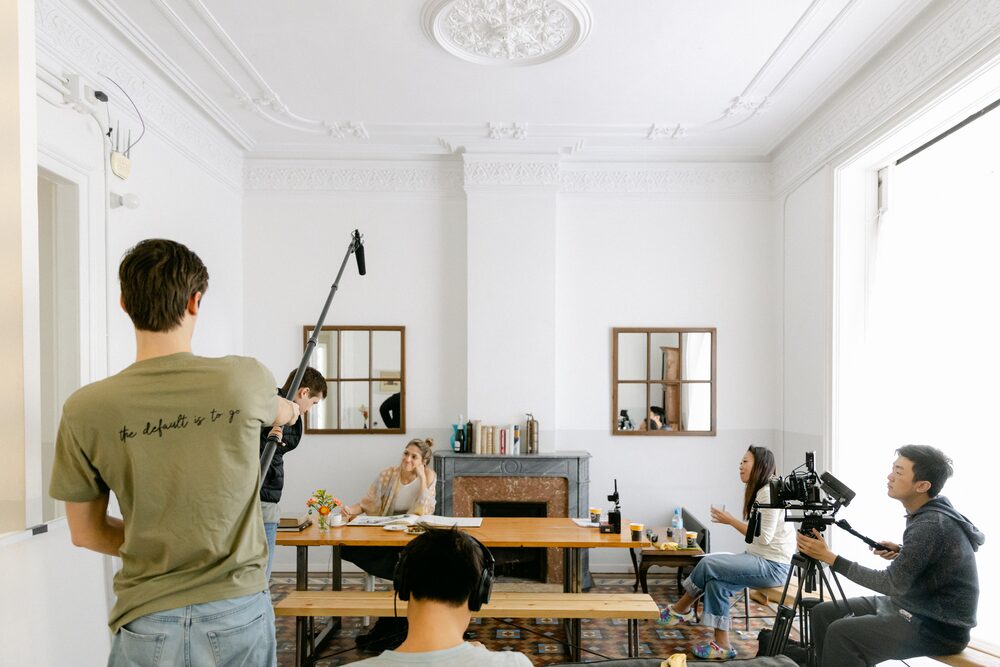 Crew filming a scene in a bright room with a boom microphone