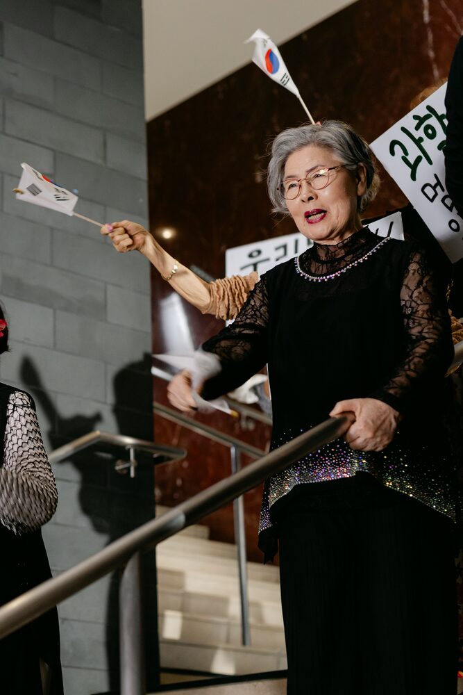 Older woman waving small flags on a staircase