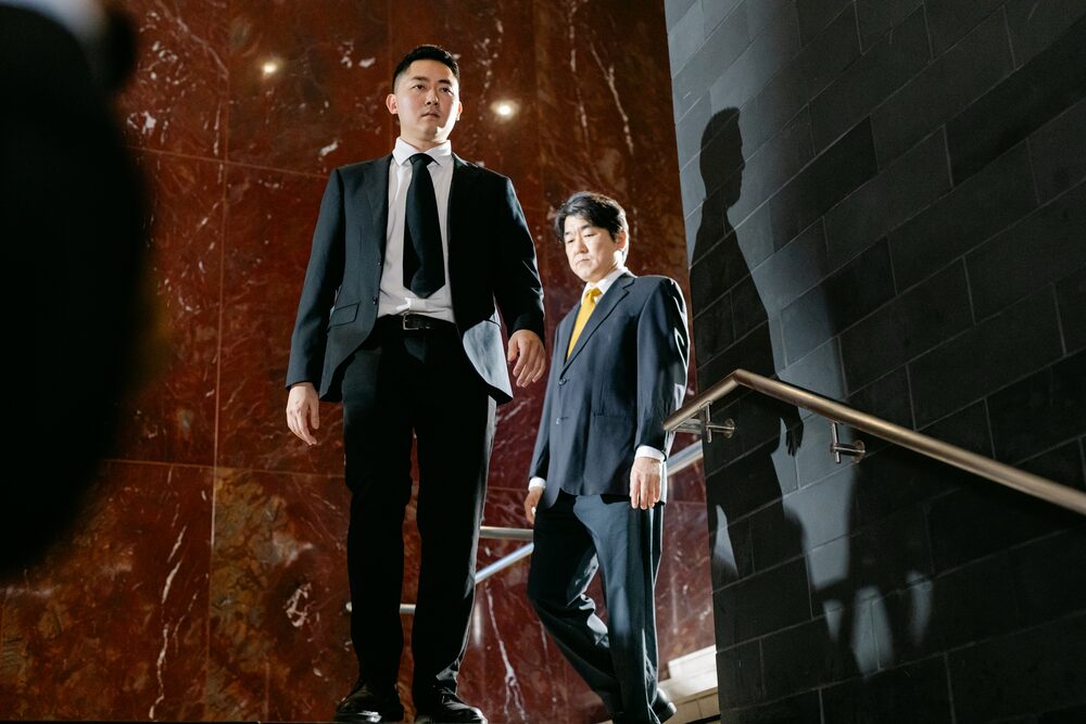 Two men in suits descending a marble staircase