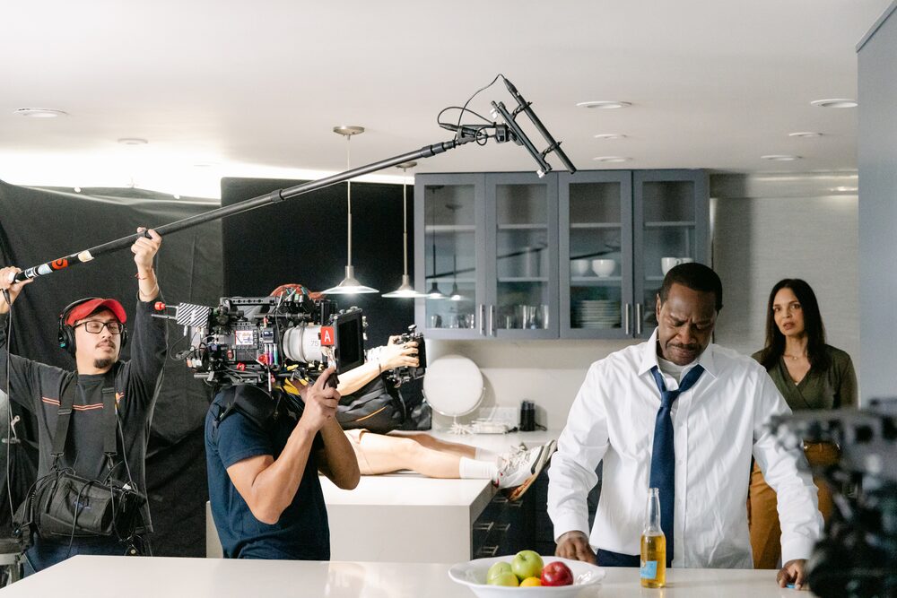 Camera crew filming two actors in a kitchen