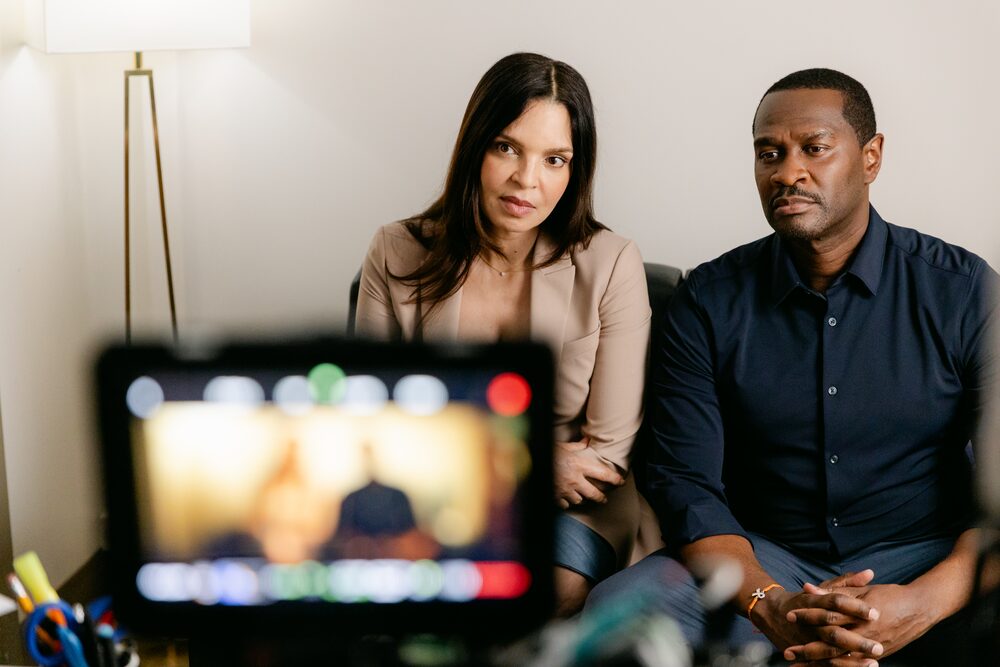 Couple on a sofa framed by a monitor in the foreground