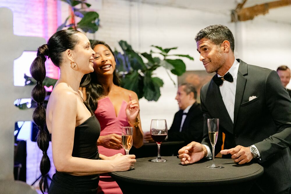 Guests in evening wear chatting at a cocktail table