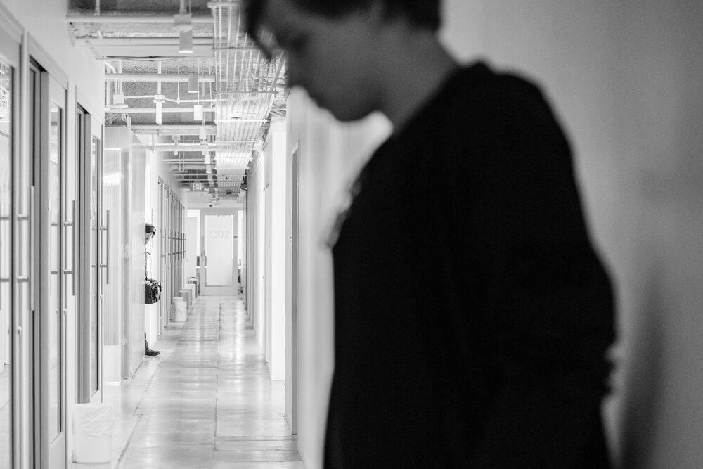 Black and white profile of a man in a dark coat in a corridor