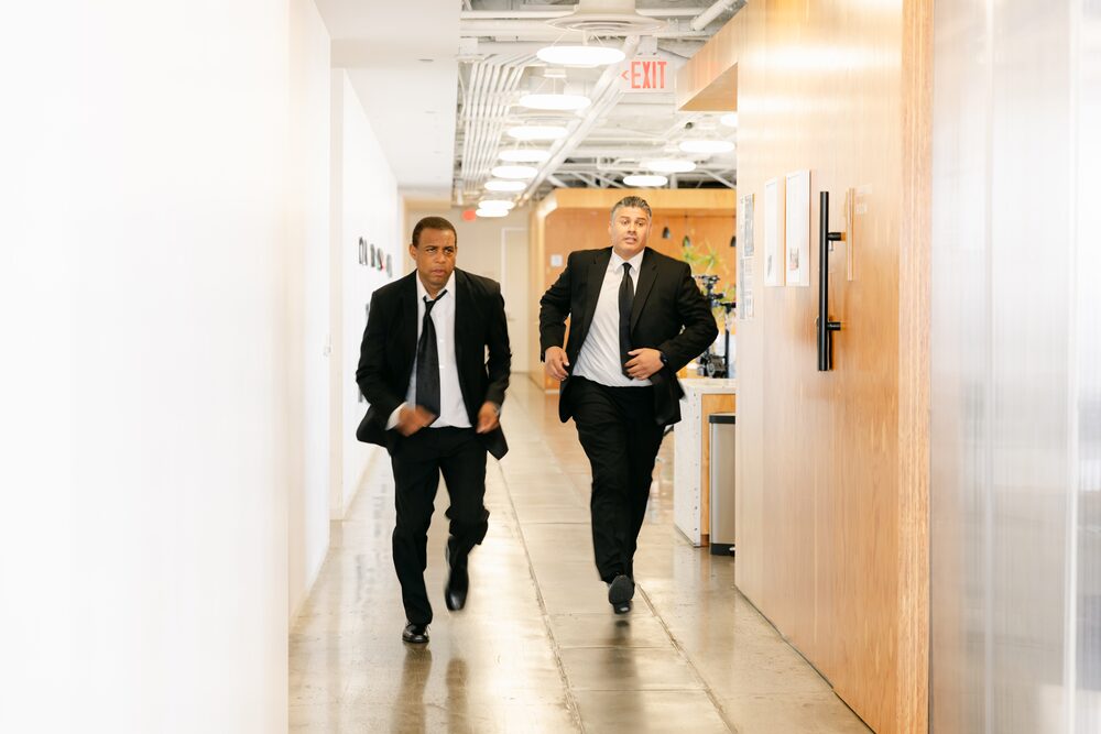Two men in suits walking down an office hallway
