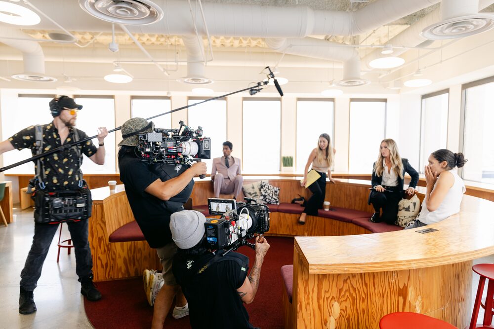 Camera crew filming a scene in a bright lounge