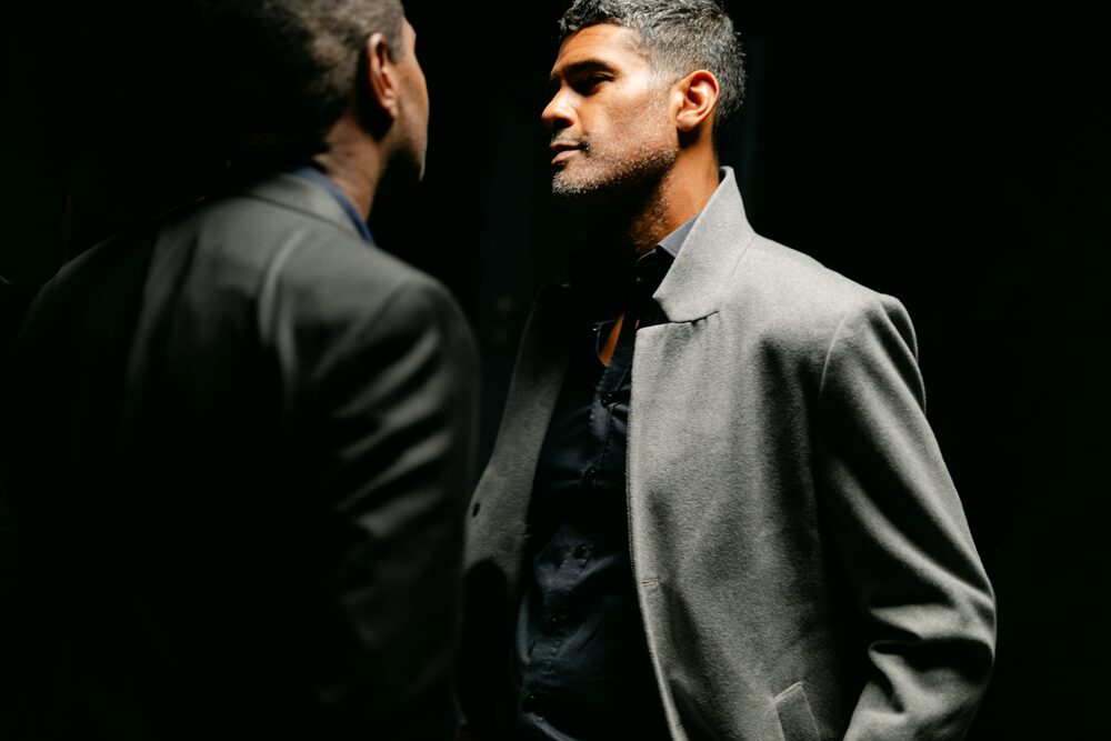 Two men in suits facing each other in low light